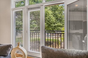 Ein Zimmer mit einer großen Schiebeglasdoor, die auf einen Balkon mit Metallgeländer führt.