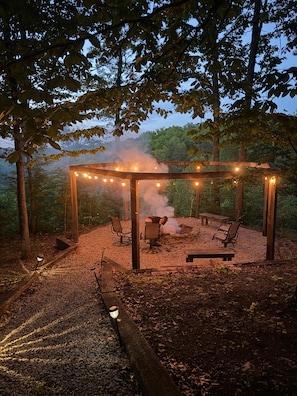 Un belvédère extérieur agrémenté de guirlandes lumineuses, d’un foyer et de sièges.