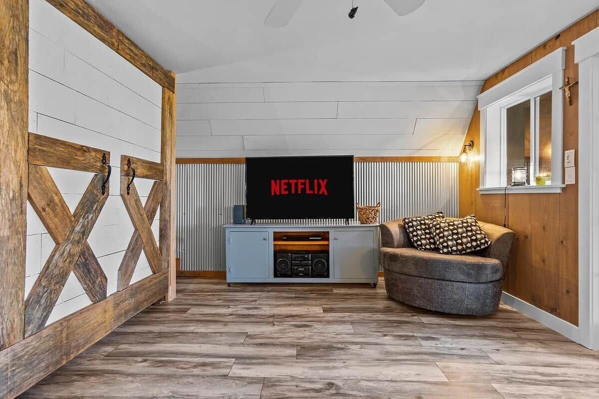 A living room with a television mounted on a wall, a sofa, and a wooden floor.