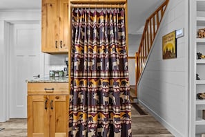 Un couloir avec un meuble en bois, un coin cuisine et un escalier.