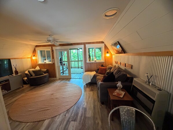 Ein gemütliches Wohnzimmer mit Fernseher, einer Couch und einem großen Teppich.