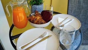 A breakfast setting with a pitcher of orange juice, a bowl of pastries, and a plate with cutlery. - Lavrio residence Corfu (Ypsos)