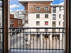 Ein modernes Gebäude mit Balkon, Straßenansicht und blauem Himmel.