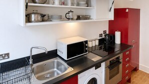 Una cucina compatta con lavatrice, forno a microonde e lavandino.