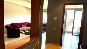 Un amplio espacio de sala con un sofá rojo, un sofá estampado y una mesa de centro de madera.