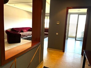 Un amplio espacio de sala con un sofá rojo, un sofá estampado y una mesa de centro de madera.