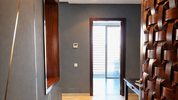 Un pasillo con alfombra oscura, paneles de madera en las paredes y una puerta que da a un balcón.