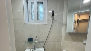 Ein Badezimmer mit weißem Waschbecken, Toilette, Dusche und Spiegel.