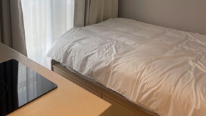 Ein Hotelzimmer mit Bett, Nachttisch, Schreibtisch und Klimaanlage.