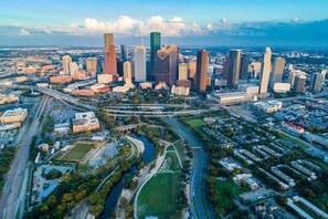 A cityscape with a prominent skyscraper, a river, and a highway interchange. - Modern Cozy 2BR Near Downtown Houston + Parking (Houston)