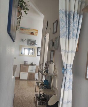 A hallway with a mirror, a shelf with items, and a patterned curtain. - Dalhia's House: stunning gulf and mountain views, Wi-Fi, A/C Free parking (Cala Gonone)