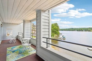En balkon med udsigt over et sølandskab, en hængekøje og udendørs møbler.