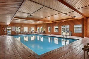 An indoor swimming pool with wooden walls and ceiling, tiled floor, and clear pool rules sign. - Suzanne`s Beachfront Penthouse (Wisconsin Dells)
