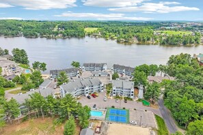 Et hotel ved søen med flere bygninger, en swimmingpool og en tennisbane.