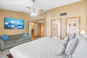 A bedroom with a bed, a ceiling fan, a TV displaying streaming services, and a sign on the wall. - Suzanne`s Beachfront Penthouse (Wisconsin Dells)