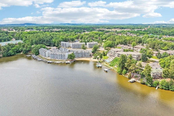 A lakeside hotel with multiple buildings, docked boats, and surrounding greenery.