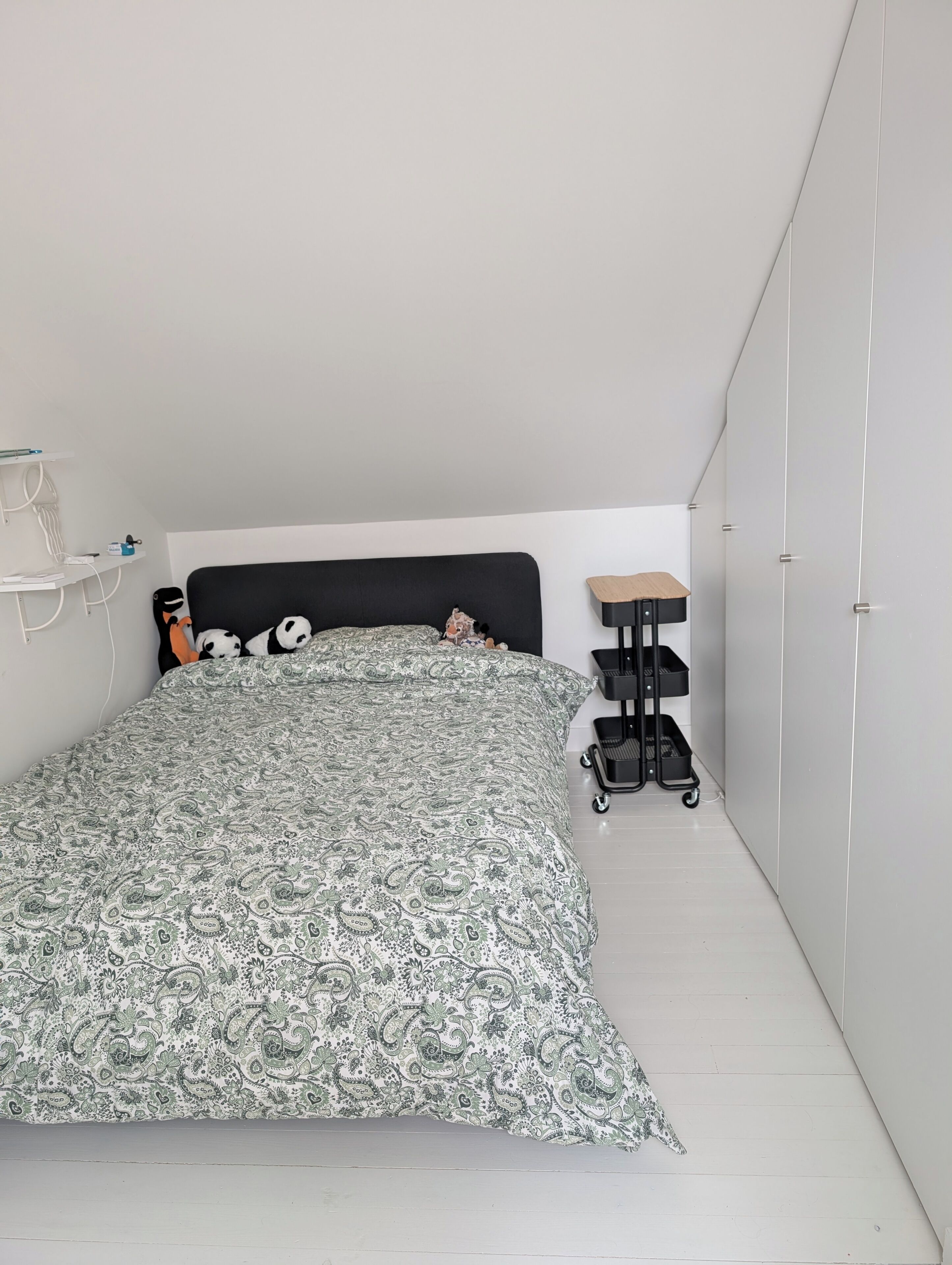 Un dormitorio con cama, un escritorio pequeño, una silla y un armario.