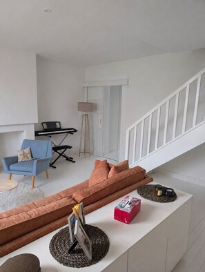 A modern living room with a sofa, a chair, a small table, a lamp, and a keyboard. - Charming house 500 m from the beach - Kerroc'h (Ploemeur)