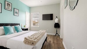 Een slaapkamer met een bed, een televisie en een etalagepop.