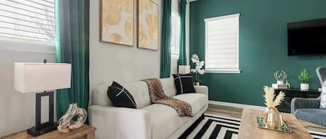 Ein Wohnzimmer mit Sofa, Couchtisch und einem an der Wand befestigten Fernseher.
