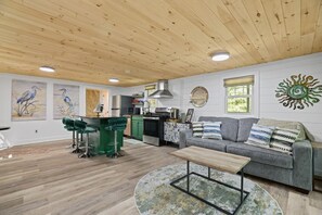 A spacious living area with a wooden ceiling, a green bar area, a grey sofa, and a round coffee table. - Robin`s Rest, Saylors Lake w/ Pond & Fire Pit (Saylorsburg)