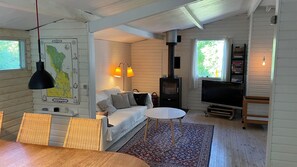 L’intérieur d’un chalet accueillant, avec un canapé, un téléviseur, une table à manger et une carte accrochée au mur.