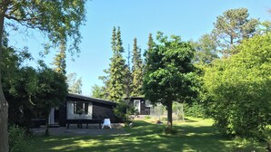A cabin with a patio, surrounded by trees and a clear sky. - Charming 2-bedroom cottage in Kulhuse, with a wonderful garden, close the beach (Kulhuse)