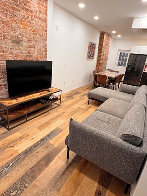 A living room with a TV, sofa, and dining area. - 5BR Jersey City Home – Perfect for World Cup Groups! 
Walk to the PATH train. (Jersey City)