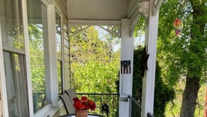 Eine überdachte Veranda mit Tisch, Stühlen, einer Topfpflanze und einem Geländer.