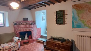 Ein gemütliches Wohnzimmer mit Kamin, Sofa, einer Karte an der Wand und einer Heizung.