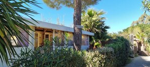 A building with a sign reading 'Kama-Holidays.de' surrounded by lush greenery and a clear sky. - Mobile home for rent at the Plage de Pampelonne St. Tropez-Ramatuelle (Saint-Tropez)