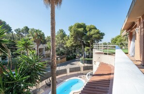 Zona de piscina con vista despejada del paisaje circundante, incluyendo árboles y un edificio.