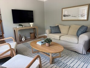 Ein Wohnzimmer mit Sofa, Couchtisch, Fernseher und Kunstwerken.