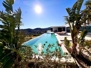 A modern pool with a clear view of the surrounding landscape, a sunlit sky, and a building with a flat roof. - Luxury villa sea view heated pool 10 pers - Golf de Saint-Tropez les Issambres (Roquebrune-sur-Argens)