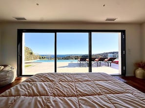 A bedroom with a large bed, a sliding glass door leading to a pool and lounge chairs, and a view of the landscape. - Luxury villa sea view heated pool 10 pers - Golf de Saint-Tropez les Issambres (Roquebrune-sur-Argens)