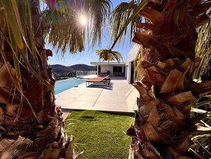 A modern outdoor pool area with a view of mountains, surrounded by palm trees and a clear sky. - Luxury villa sea view heated pool 10 pers - Golf de Saint-Tropez les Issambres (Roquebrune-sur-Argens)