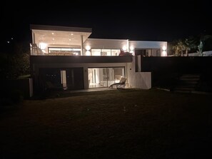 A modern two-story house with a large glass door entrance, a balcony, and a well-lit interior. - Luxury villa sea view heated pool 10 pers - Golf de Saint-Tropez les Issambres (Roquebrune-sur-Argens)