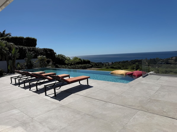 A swimming pool with lounge chairs and a view of the sea. - Luxury villa sea view heated pool 10 pers - Golf de Saint-Tropez les Issambres (Roquebrune-sur-Argens)