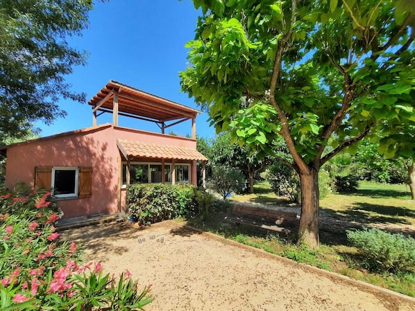 A rustic house with a tiled roof, a covered porch, and a garden with various plants and a tree. - A quiet home in a little slice of paradise - Pétanque court (Roquebrune-sur-Argens)