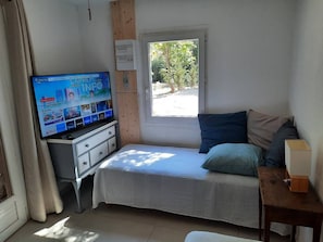 A bedroom with a bed, a TV on a dresser, a window, and a small table. - A quiet home in a little slice of paradise - Pétanque court (Roquebrune-sur-Argens)