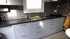 A modern kitchen with grey cabinets, a black countertop, and a window above the sink.