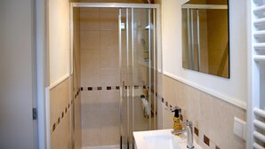 A modern bathroom with a glass-enclosed shower, a white sink, and a mirror.