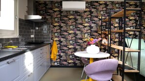 A compact kitchen with a modern sink, a small dining table with a vase of flowers, and a chair.