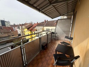 Ein Balkon mit Metallgeländer, einem Tisch und zwei Stühlen.