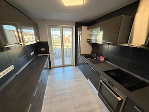 Een moderne keuken met donkere kastjes, een ingebouwde oven en een groot raam.