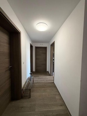 En smal gang med trædøre, en radiator og en loftlampe.