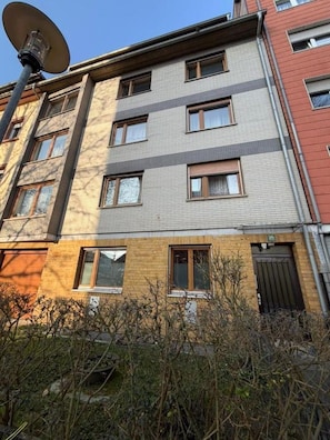 Een meerlaags gebouw met een schotelantenne, meerdere ramen en een deur.