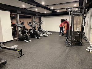 A gym with treadmills, a rowing machine, and weightlifting equipment.