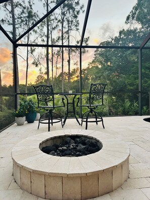 Eine Terrasse im Freien mit Feuerstelle, zwei Stühlen und einem Tisch.