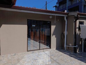 A building with a large glass door, a tiled patio, and a satellite dish. - Crompton Studio Apartment 786 (Durban)